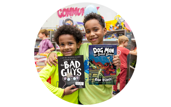 Two students smile while showing off their new books from the Book Fair
