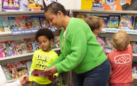 A Book Fair volunteer reads through a book with a student at their Book Fair