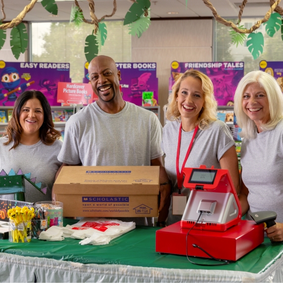 A group of Book Fair volunteers smile around the cashier table 