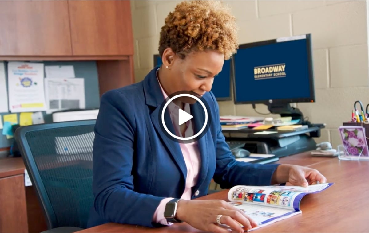 A Host browses a Scholastic Dollars catalog at their desk 